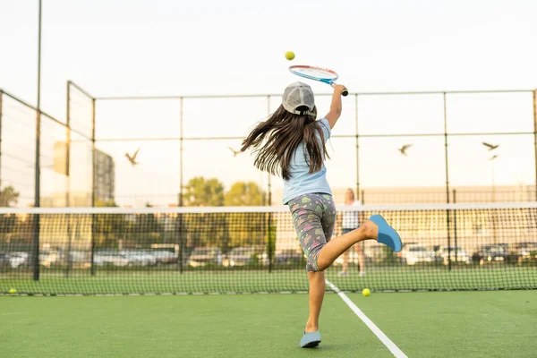 Petite fille essayant de jouer au tennis sur le court extérieur — Photo