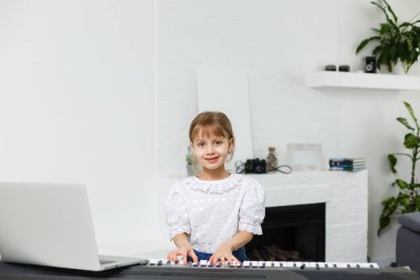 Karantina sırasında piyano öğrenen küçük bir kız. Coronavirus konsepti.