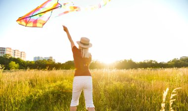 Yeşil alana uçurtma fırlatan genç ve kaygısız bir kadının portresi. Doğada aktif yaşam tarzı kavramı