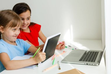 Evdeki online dersi sırasında öğrenim gören oldukça şık liseli kızlar, karantina sırasındaki sosyal mesafeler, kişisel izolasyon, online eğitim konsepti