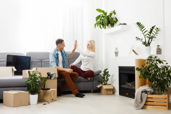 Lachend koppel zit op de vloer weg te kijken van de camera — Stockfoto