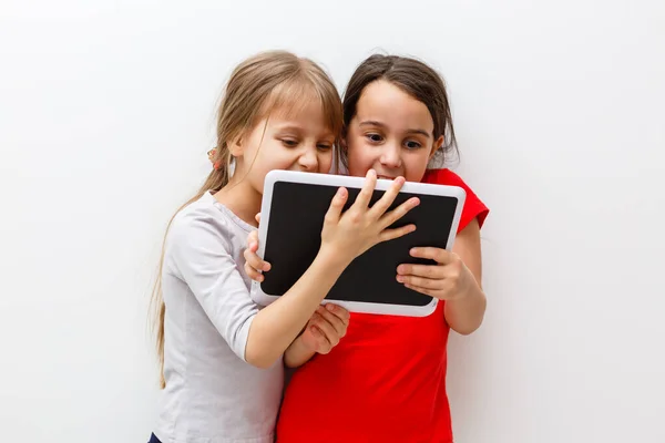 Kleine meisjes spelen op een tablet computer apparaat zitten op de vloer — Stockfoto