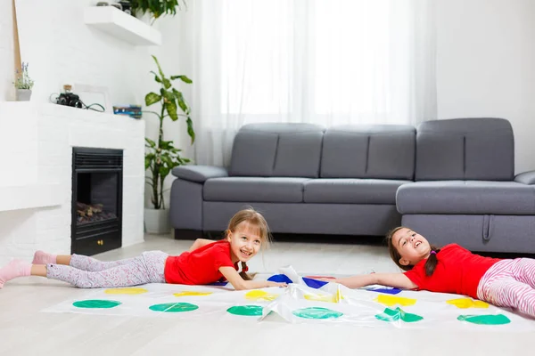 Dos niñas felices en ropa de niños juegan con entusiasmo en el suelo. — Foto de Stock