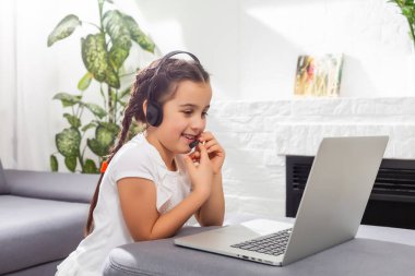 Küçük kız Studen evde dizüstü bilgisayarla online ders çalışıyor. Covid-19 koronavirüs. Sosyal uzaklık, evde eğitim..
