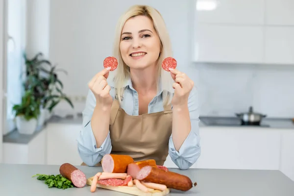 La fille mange des saucisses. Un morceau de saucisse. Sourire et joie. Le concept d'entreprise est l'attrait des marques. Appétit — Photo