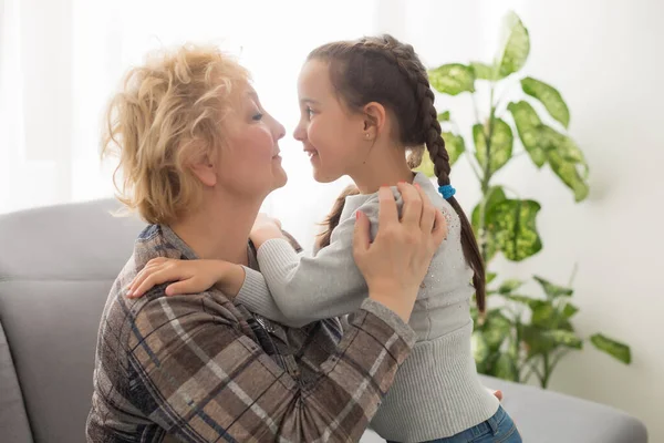 Senior Woman Hugging Granddaughter While Sitting Sofa Home — Stock Photo, Image