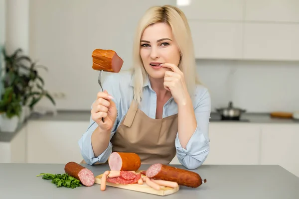 Attraente giovane donna che tiene una salsiccia su una forchetta — Foto Stock