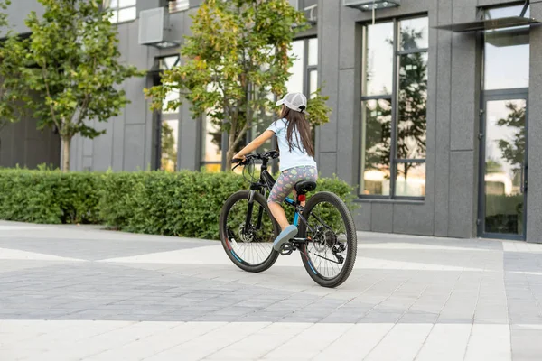 Adorable niñita montando en bicicleta en una ciudad — Foto de Stock