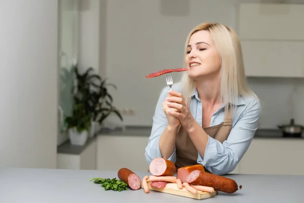 Attraente giovane donna che tiene una salsiccia su una forchetta — Foto Stock