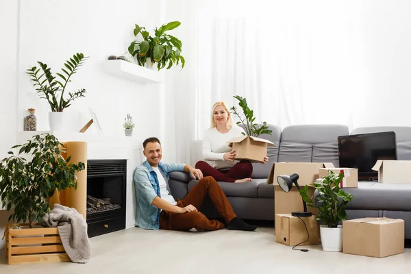 Smiling couple sitting on the floor looking away from the camera — Stock Photo, Image