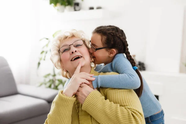 Senior Woman Hugging Granddaughter While Sitting Sofa Home — Stock Photo, Image