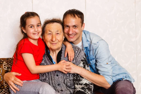 95-jarige vrouw en haar achterkleindochter kijken naar de camera. Ze zit op een stoel in haar woonkamer.. — Stockfoto