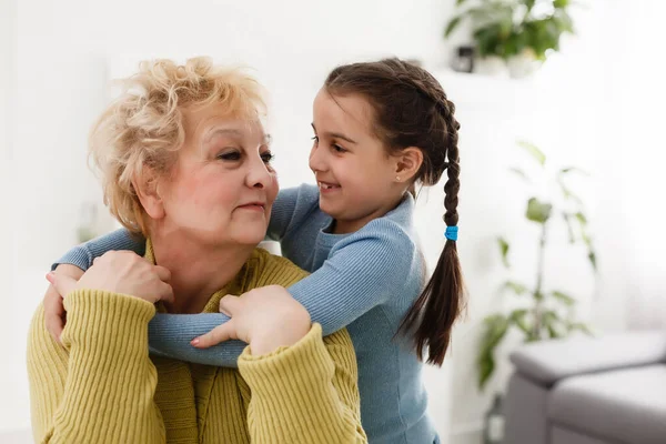 Senior Woman Hugging Granddaughter While Sitting Sofa Home — Stock Photo, Image