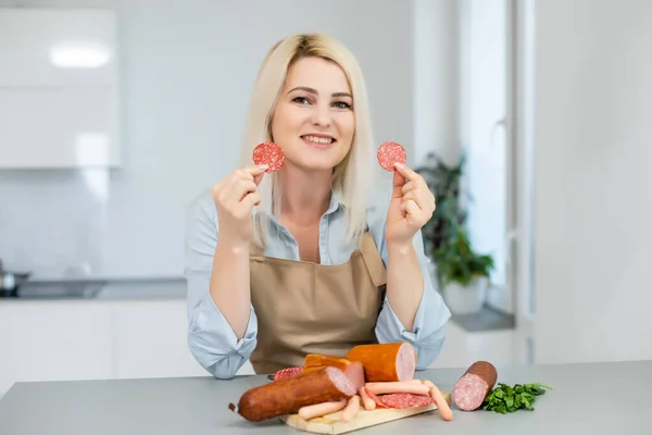 La chica está comiendo salchicha. Un trozo de salchicha. Sonrisa y alegría. Concepto de negocio es el atractivo de las marcas. Apetito — Foto de Stock