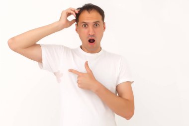 Adam beyaz tişörtünde bir leke gösteriyor.