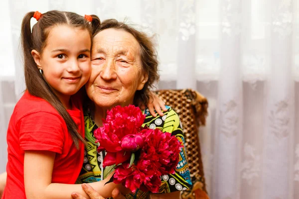 Little girl giving her great grandmother a pink flower — Stock Photo, Image