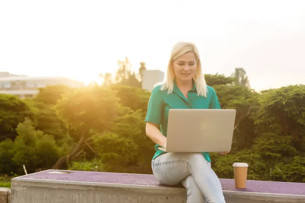 Woman with laptop in the garden. Business online in the fresh air. The girl working remotely autdoor