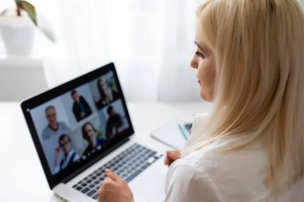 Vue arrière de femme d'affaires parlant à ses collègues au sujet du plan en vidéoconférence. Équipe d'affaires multiethnique utilisant un ordinateur portable pour une réunion en ligne en appel vidéo. Groupe de personnes intelligentes travaillant à domicile — Photo