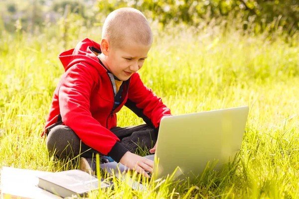 Distance learning. Boy learns autdoor laptop. Doing homework on grass. The child learns in the fresh air. The childs hands and computer — Stock Photo, Image