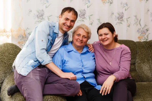 Volwassen lachende kleinkinderen omhelzen oudere grootmoeder blij haar te zien missen, bezoek van liefdevolle familieleden genieten van communicatie, knuffelen als symbool van verbondenheid, liefde en steun concept — Stockfoto