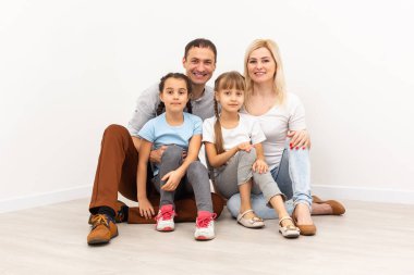 Ahşap zeminde oturan mutlu aile. Baba, anne ve çocuk birlikte eğleniyorlar. Taşınma günü, yeni ev konsepti