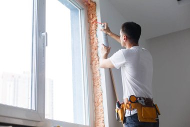 Yeni bir eve pencere ve duvar arasına dolgu yapan bir adam