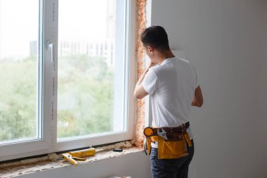 Yeni bir eve pencere ve duvar arasına dolgu yapan bir adam