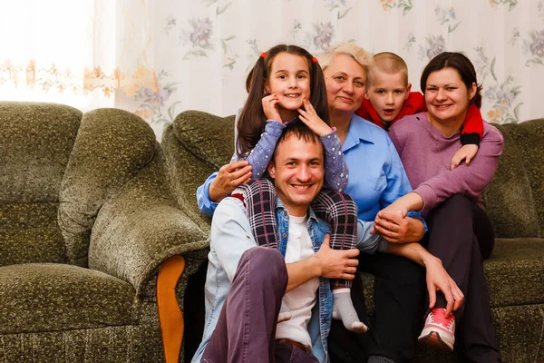 Grootmoeder en kleinkinderen zitten samen op de bank in de woonkamer — Stockfoto