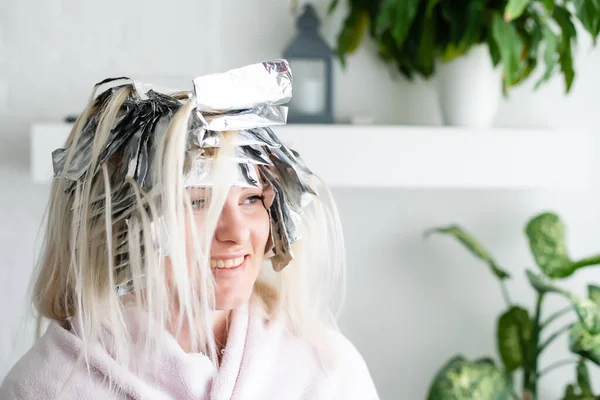 Mulher bonita com papel alumínio em seu cabelo. Processo de branqueamento ou tingimento em casa — Fotografia de Stock