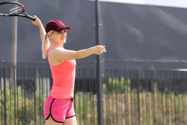 Femme jouant au tennis tenant une raquette et souriant — Photo
