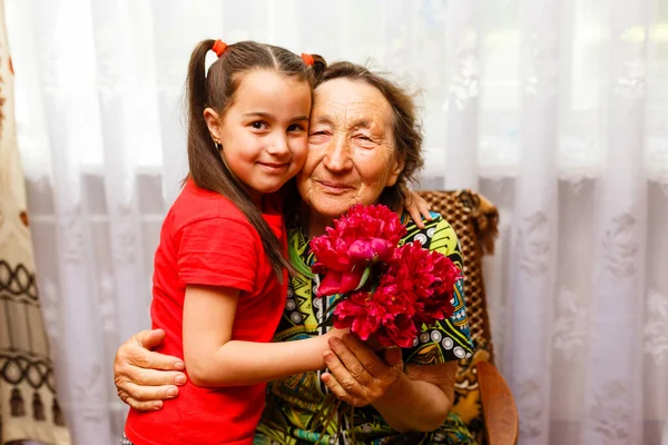 Маленька дівчинка відвідує свою хвору бабусю, даруючи квіти — стокове фото