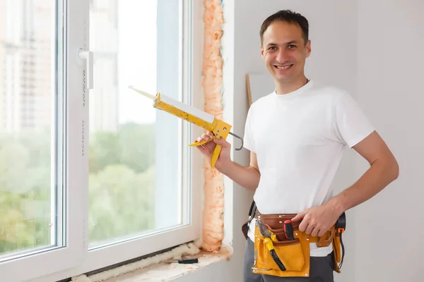 Man sätter fyllning mellan fönster och vägg i ett nytt hus — Stockfoto