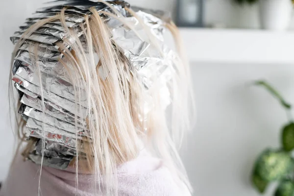 Mulher bonita com papel alumínio em seu cabelo. Processo de branqueamento ou tingimento em casa — Fotografia de Stock