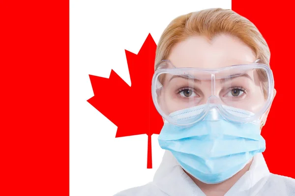 Ragazzina mascherata che guarda la telecamera sullo sfondo della bandiera canadese. Il concetto di attenzione alla diffusione mondiale del coronavirus in tutto il mondo. Coronavirus, virus in Canada. — Foto Stock