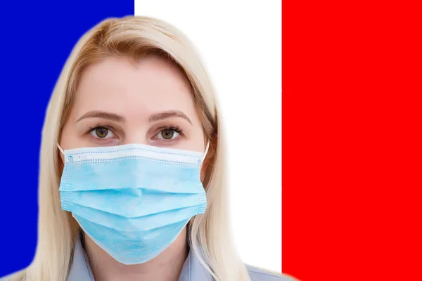 Cara de mujer enmascarada mirando la cámara en el fondo de la bandera de Francia. El concepto de atención a la propagación mundial del coronavirus en todo el mundo. Coronavirus, virus en Francia. —  Fotos de Stock