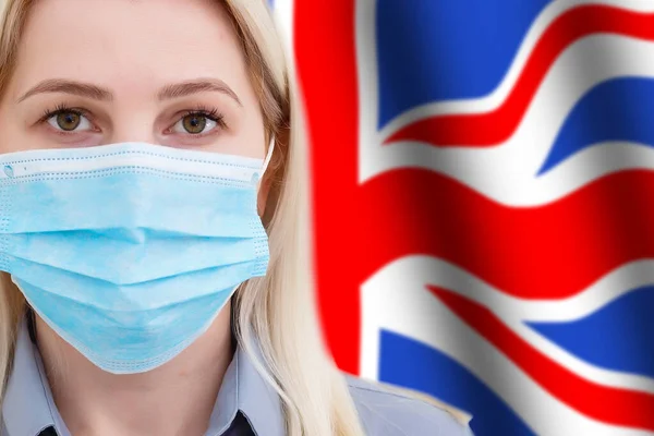 戴面具的女人面对着英国国旗背景上的相机。关注世界范围内的头孢病毒传播的概念。Coronavirus，病毒在英国. — 图库照片