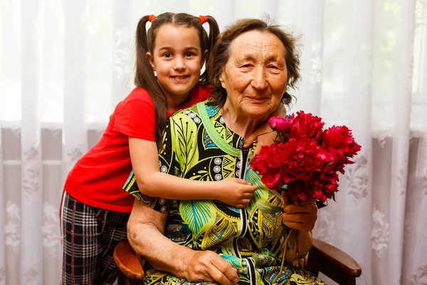 Menina dando a sua bisavó uma flor rosa — Fotografia de Stock