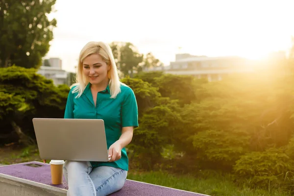 Женщина ищет работу с ноутбуком в городском парке летом — стоковое фото