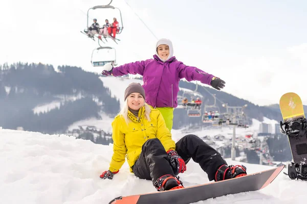 Madre e hija con tablas de snowboard juegan en la nieve — Foto de Stock