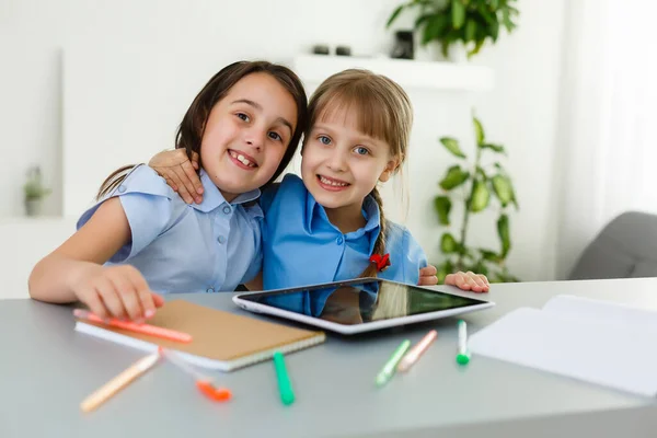 Colegialas bastante elegantes que estudian durante su lección en línea en casa, distancia social durante la cuarentena, auto-aislamiento, concepto de educación en línea — Foto de Stock