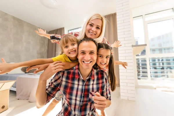 Lycklig familj mor, far och två barn leker och gosar hemma — Stockfoto