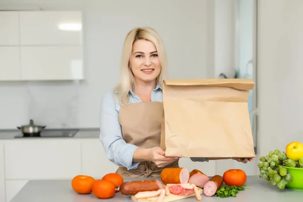 Αντίληψη αυτο-απομόνωσης. γυναίκα ξεπακετάρει χάρτινη σακούλα με φαγητό στην κουζίνα, έτοιμη για καραντίνα κατά τη διάρκεια επιδημικής έξαρσης — Φωτογραφία Αρχείου