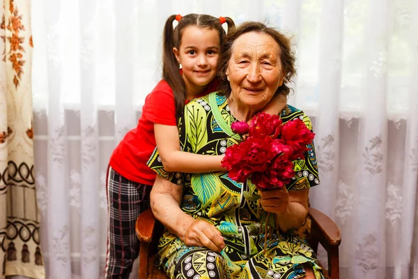 Menina visitando sua avó doente dando flores — Fotografia de Stock