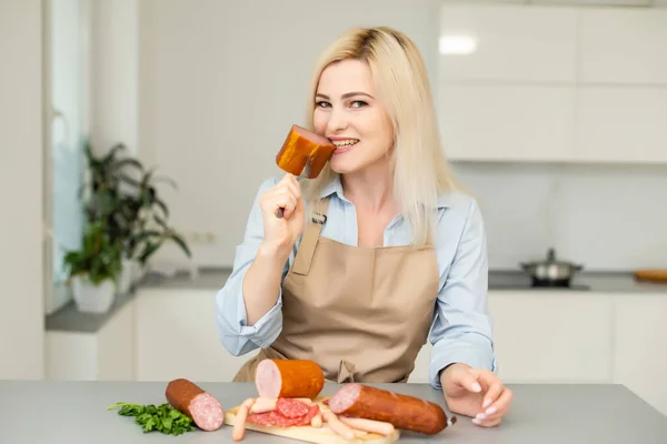 Het meisje eet worst. Een stuk worst. Lachen en Vreugde. Bedrijfsconcept is de merken beroep. Eet smakelijk — Stockfoto