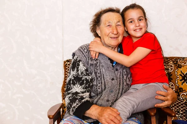 Conceito de ligação familiar. Linda menina feliz emracing sua avó na sala de estar leve — Fotografia de Stock
