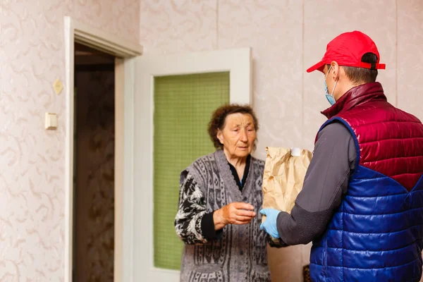 Una anciana se queda en casa. Entrega de comida en una máscara médica a los ancianos. —  Fotos de Stock