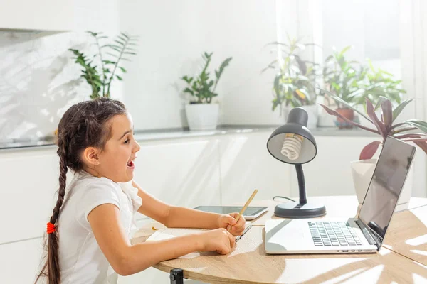 Foto van positieve kid meisje studie remote zitten bureau tafel gebruik laptop hebben online communicatie les met tutor schrijven verslag in huis binnen — Stockfoto