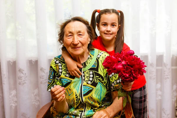 Petite fille donnant à son arrière grand-mère une fleur rose — Photo