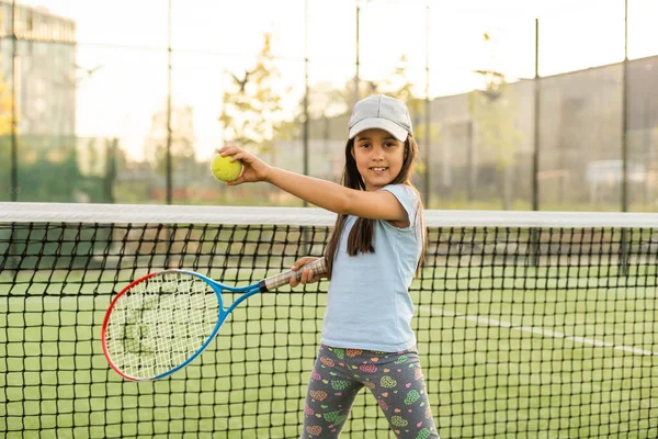 Petite fille essayant de jouer au tennis sur le court extérieur — Photo