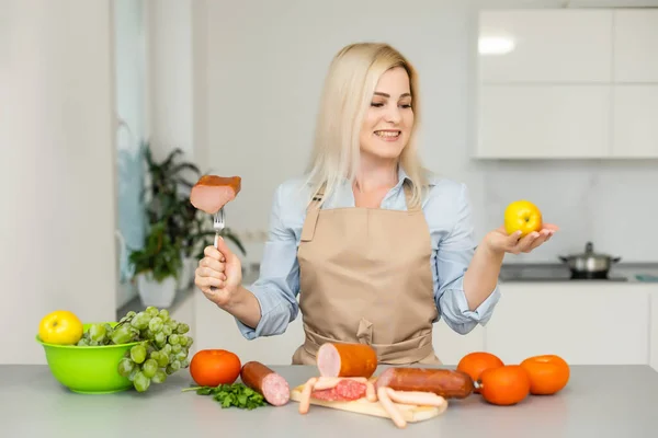 Mulher detém e escolhe entre carne e maçã — Fotografia de Stock